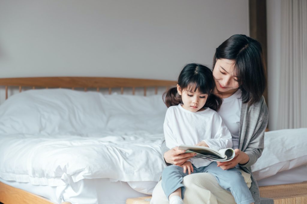 Mother and daughter reading books in bedroom