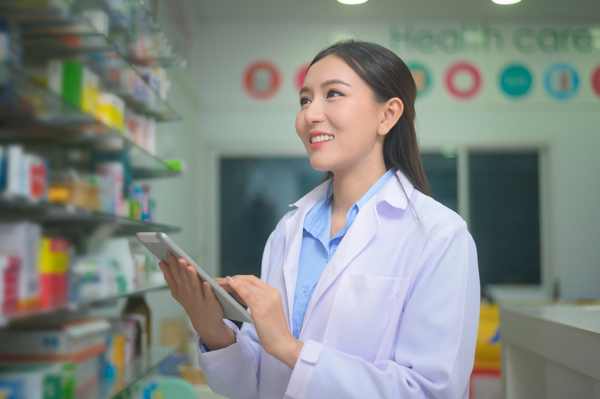 Portrait of asian woman pharmacist using tablet in a modern pharmacy drugstore.